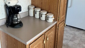 Eine Küche mit Holzausstattung, einer Kaffeemaschine und Aufbewahrungsbehältern.