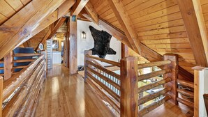Ein Holzinnenraum mit hohen Decken und einer Treppe, die zu einer oberen Ebene führt.