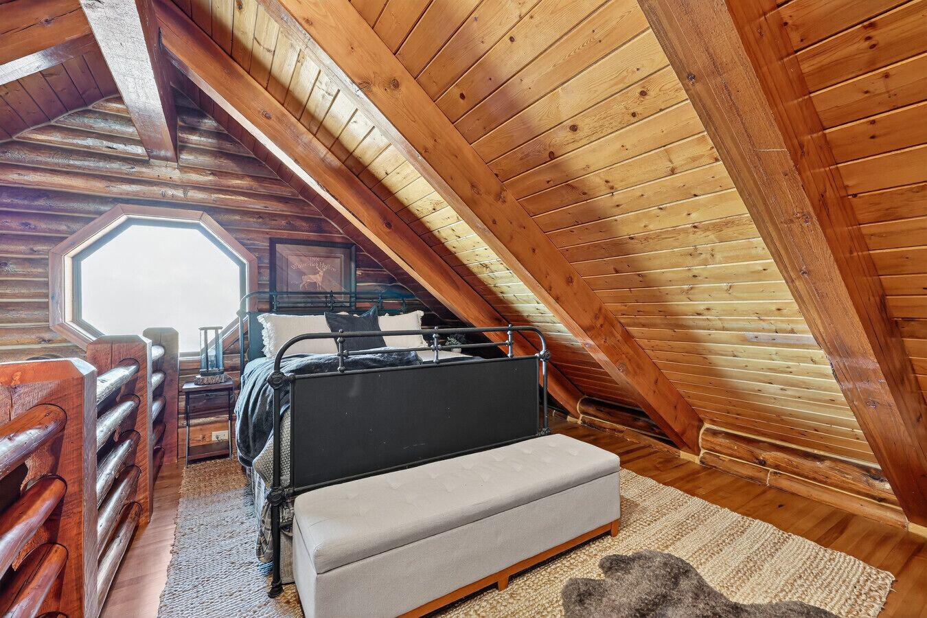 A cozy attic bedroom with a bunk bed, a small sofa, and a rustic wooden interior.
