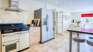 Une cuisine moderne équipée d’une cuisinière, d’un four, d’un réfrigérateur et d’un coin repas avec une table et des chaises.