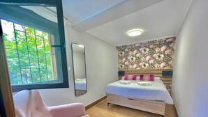 A bedroom with a bed, a chair, a window, and a mirror. - Okai Etxea Bermeo, suite in the center of the town (Bermeo)