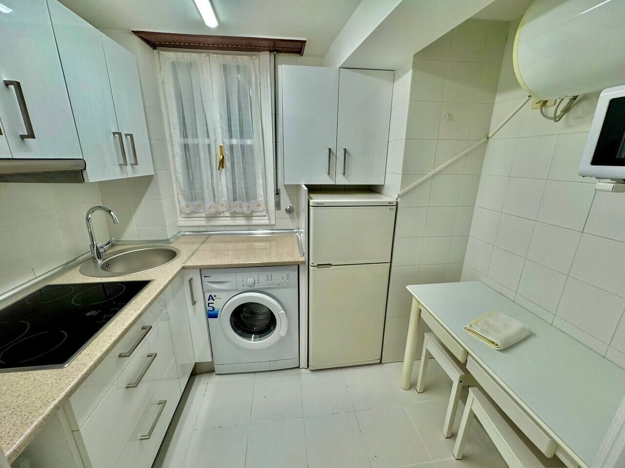 A compact kitchen with a washing machine, a sink, and a small table.
