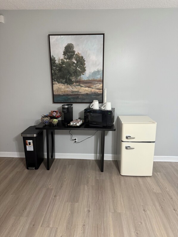A compact room with a desk, a vintage-style refrigerator, a trash bin, and a framed landscape painting on the wall. - Beautiful and conveniently located mother-in-law suite in Tallahassee (Tallahassee)