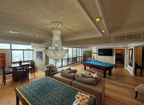 A spacious living room with a pool table, a large sofa, and a chandelier. - Spacious City View - Perfect for Families or Groups (Sleeps 10-12) (London)