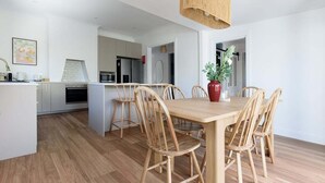 A modern kitchen with wooden cabinets, a dining table with chairs, and a hanging light fixture. - South Launceston Gem, Minutes to Cataract Gorge (Launceston City)