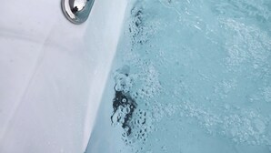 Uma banheira de hidromassagem com jatos, painel de controle e área de estar.
