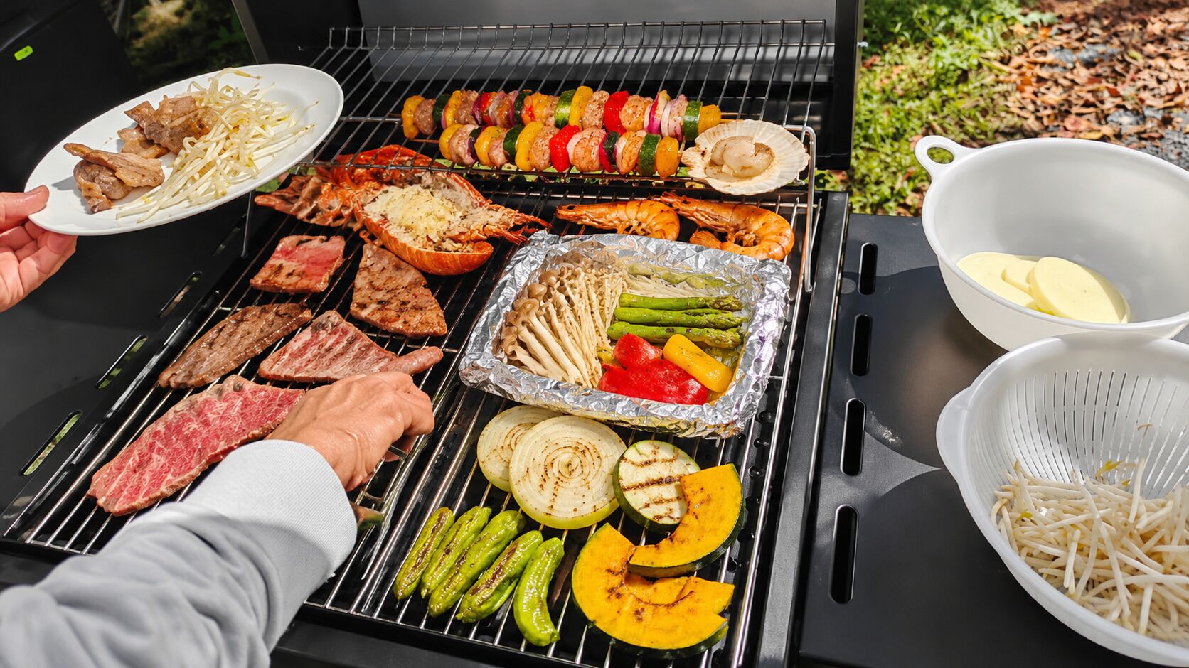 Una parrilla con diversos tipos de carne y verduras asándose.