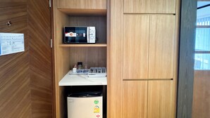 Eine kompakte Küche mit einer Mikrowelle, einem kleinen Kühlschrank und einer Arbeitsfläche mit Wasserkocher und Tassen.