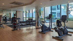 Ein modernes Fitnessstudio mit Cardiogeräten, Kurzhanteln und einem Gewichtständer.