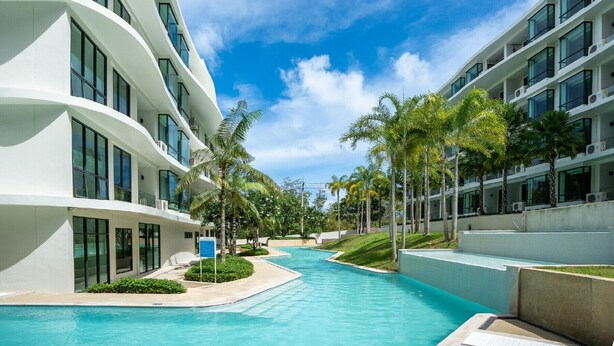 Ein modernes Hotel mit Swimmingpool, Palmen und blauem Himmel.
