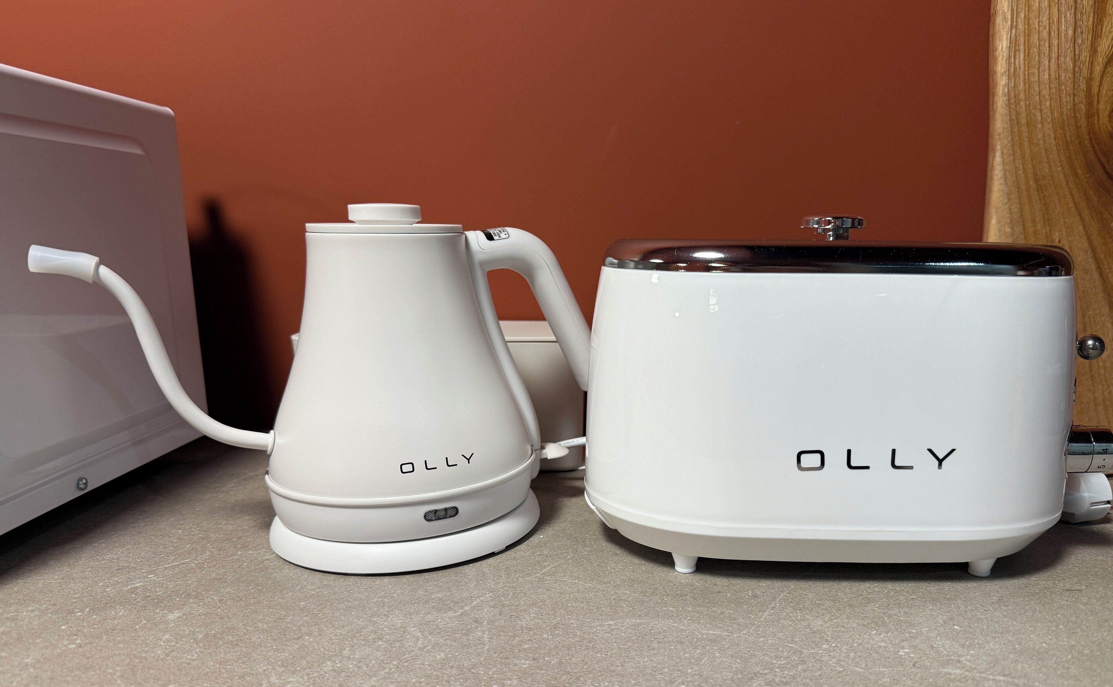 Two white OLLY appliances, a kettle and a slow cooker, on a kitchen counter.