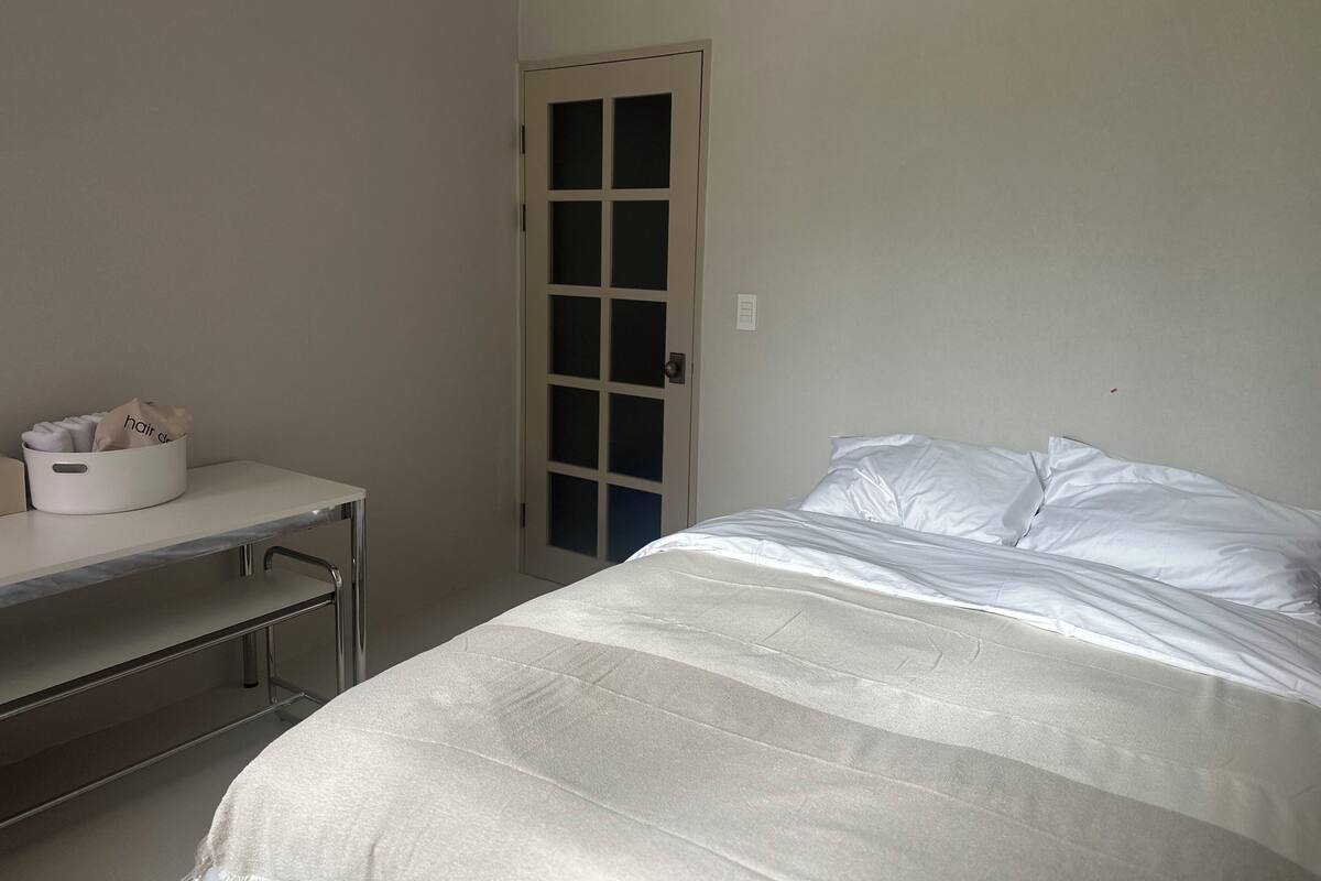 A bedroom with a bed, a desk, and a door.