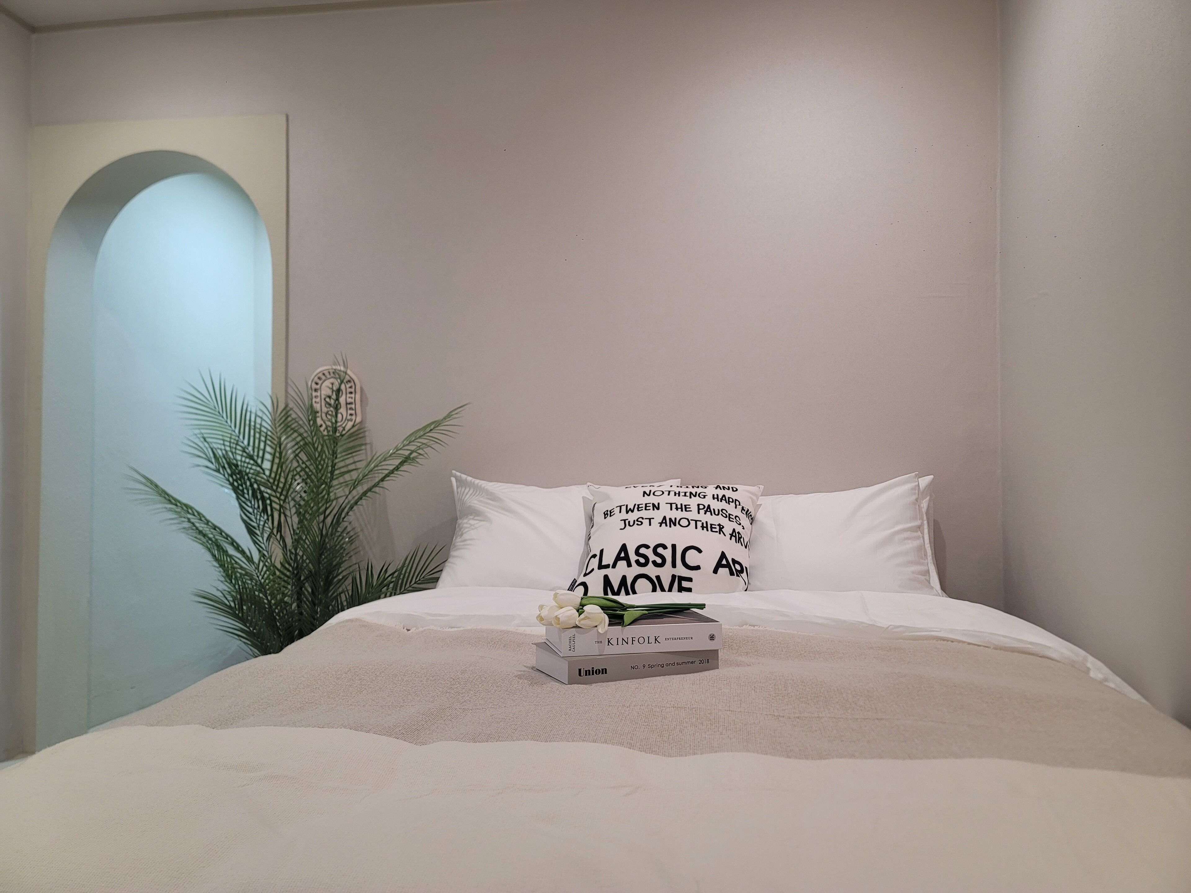 Une chambre à coucher avec un lit, une plante en pot et un luminaire fixé au mur.