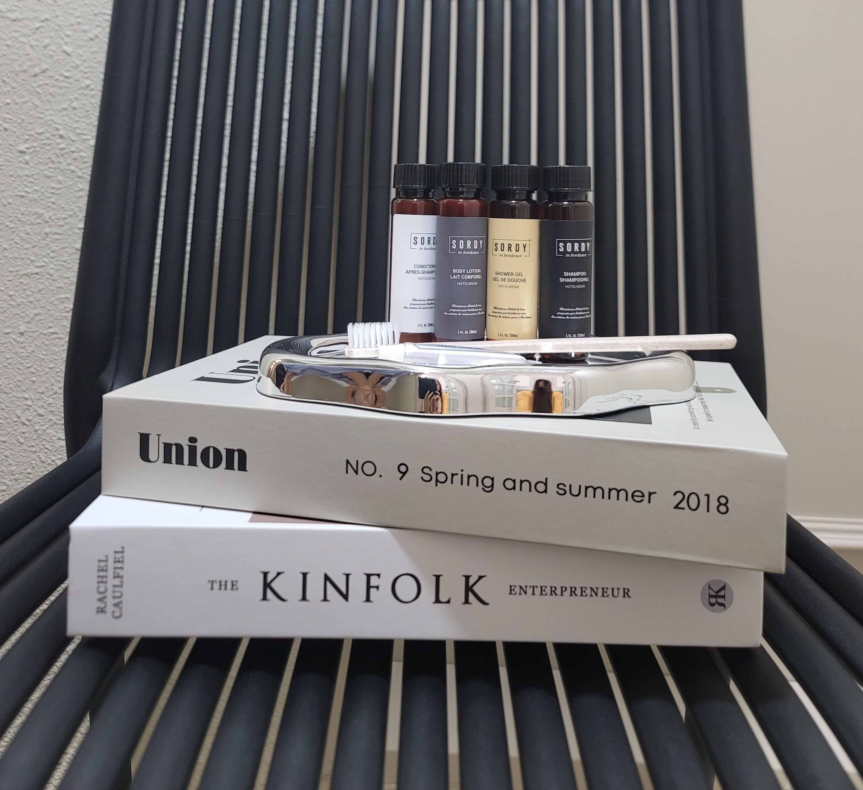 A stack of books and toiletries on a chair.