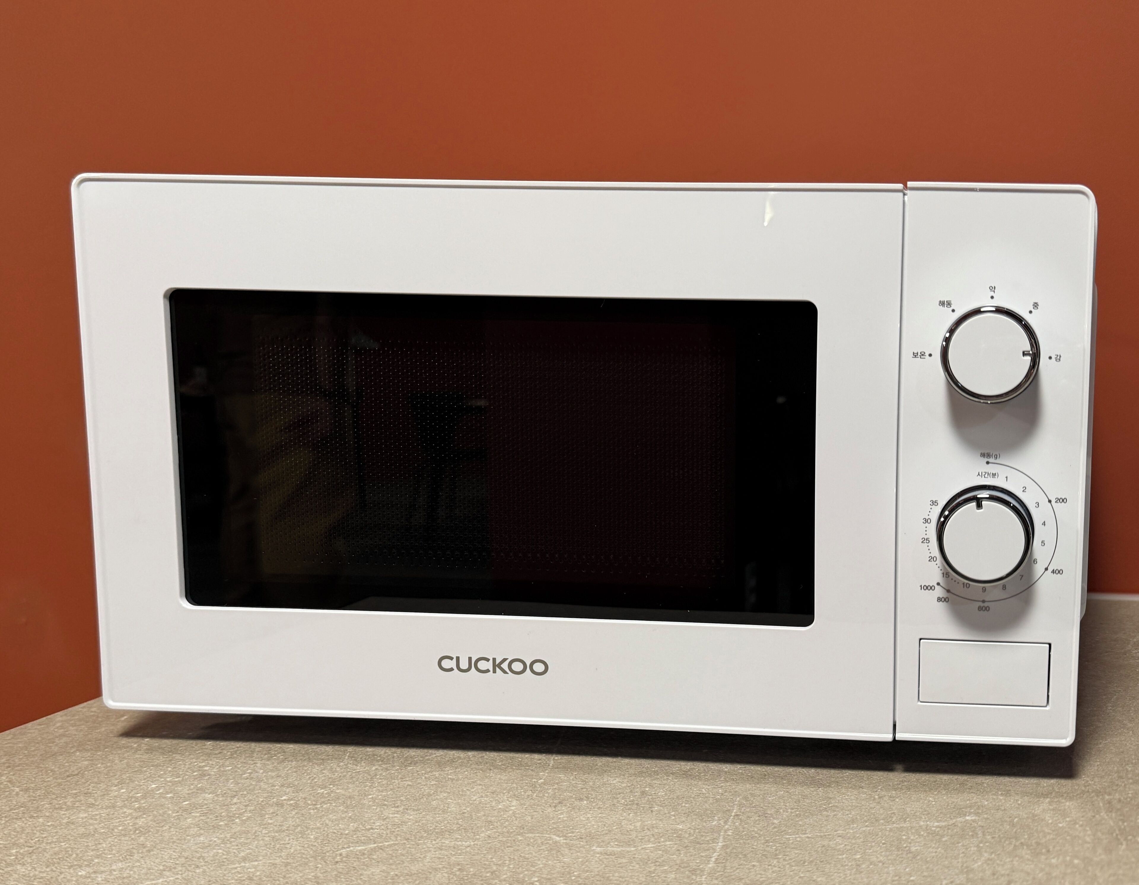 En CUCKOO mikrobølgeovn med to kontrolknapper og et digitalt display.