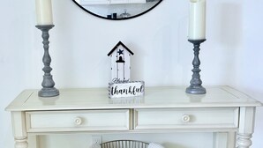 Une console blanche ornée de deux bougies, d’un miroir et d’une horloge.