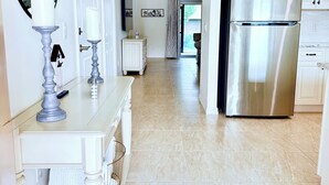 Une cuisine moderne avec des meubles blancs, un réfrigérateur en acier inoxydable et un sol carrelé.