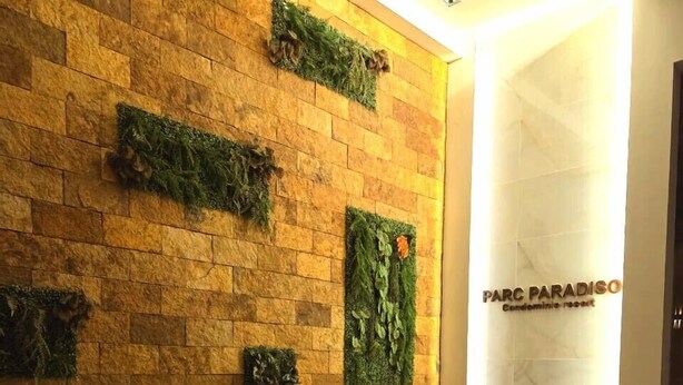 Un espace d’accueil avec un mur en pierre, un comptoir de réception portant l’inscription « Correspondance » et un panneau indiquant « PARC PARADISO ».