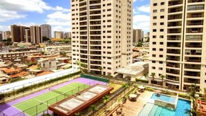 Un immeuble de grande hauteur doté de nombreux balcons, d’un court de tennis sur le toit et d’une piscine.