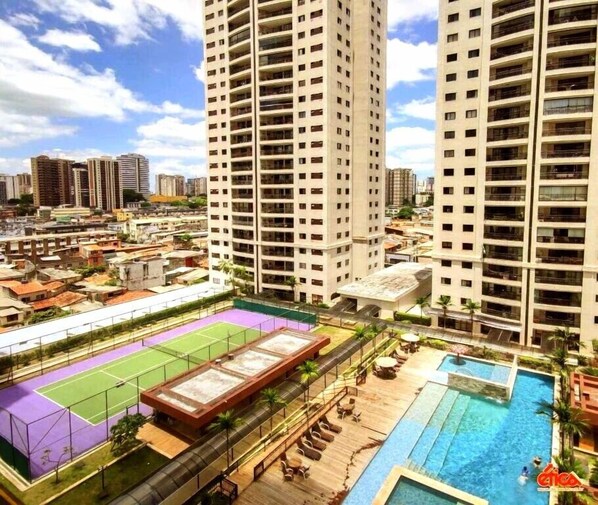 A high-rise building with multiple balconies, a rooftop tennis court, and a swimming pool. - Resort Parc Paradiso (Belem)