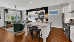 Eine moderne Küche mit Kochinsel, Barhocker und Essbereich mit Sofa und Couchtisch.