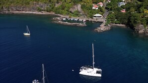 Une zone côtière où trois voiliers sont amarrés près d’une côte rocheuse.