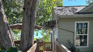 A wooden deck leading to a house with a covered porch and a large tree. - Convenient, cozy home surrounded by trees, 6 miles to BNA, 13 miles to downtown. (Hermitage)