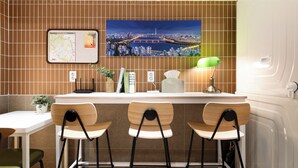 Una cocina con salpicadero de azulejos, un mapa, una lámpara verde y tres taburetes de bar.
