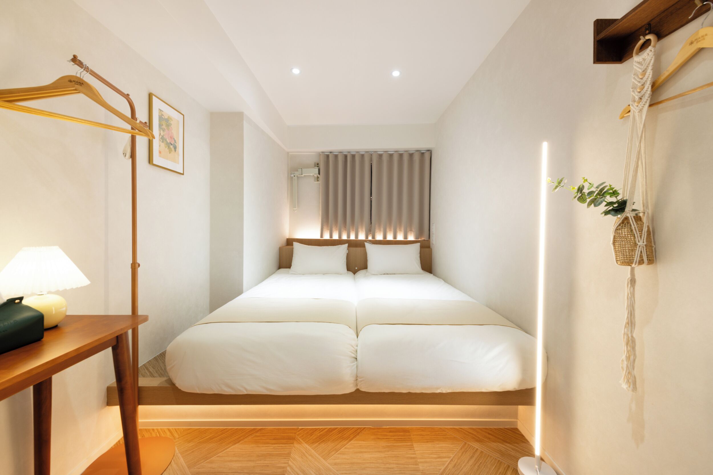 Un dormitorio ordenado con una cama doble, mesitas de noche y un adorno de macramé en la pared.