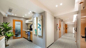 Un pasillo de hotel con un área de descanso, una kitchenette y obras de arte en las paredes.