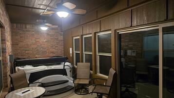 A cozy indoor space with a brick wall, a ceiling fan, and a large window.