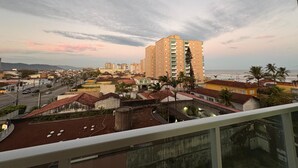 A coastal cityscape with a prominent multi-story building, a variety of residential structures, and a view of the ocean.