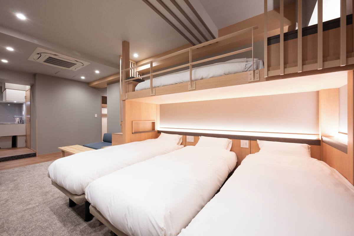 A bunk bed room with two beds, a small table, and a bench.