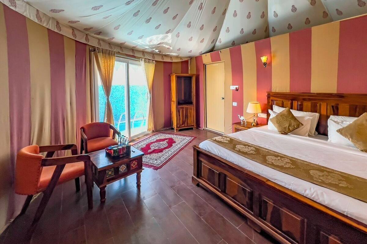 Una camera d'albergo con un letto grande, una testiera in legno, un tavolino con una lampada e una sedia.