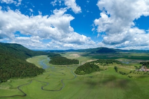 A panoramic view of a landscape with a river, forested areas, and a small settlement.