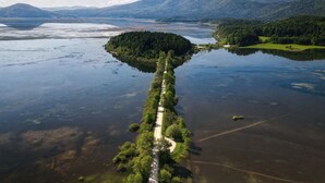 An aerial view of a lake with a narrow, tree-lined path leading to a small island. - Farm Stay Oblak Studio Ina + Shared Sauna, Ortnek, Slovenia (Ortnek)