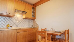 A kitchen with wooden cabinets, a tiled backsplash, a built-in stove, and a dining area with a wooden table and chairs. - Farm Stay Oblak Studio Ina + Shared Sauna, Ortnek, Slovenia (Ortnek)