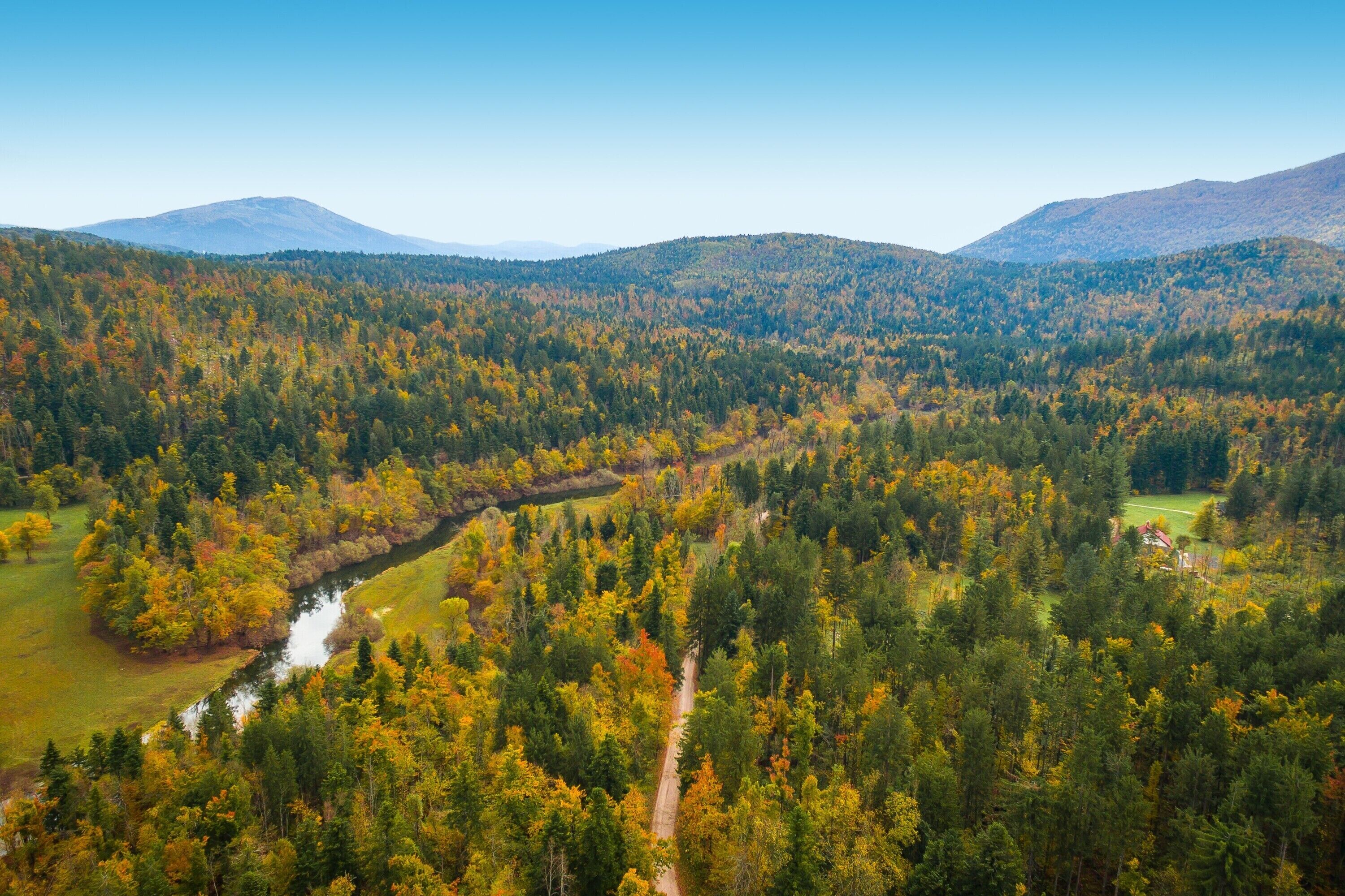 Paisagem montanhosa com um rio serpenteando por um vale florestado.