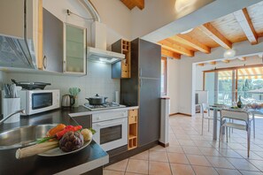 A modern kitchen with a built-in oven, microwave, and a dining area with a glass table and chairs.