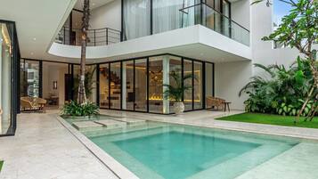 A modern house with a swimming pool, a balcony, and a well-maintained garden.