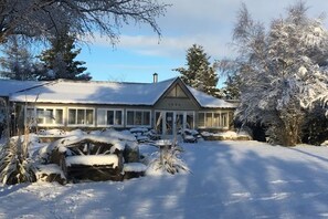 A snow-covered house with a large garage and a driveway. - Tekapo1929 Lakefront Villa (Lake Tekapo)