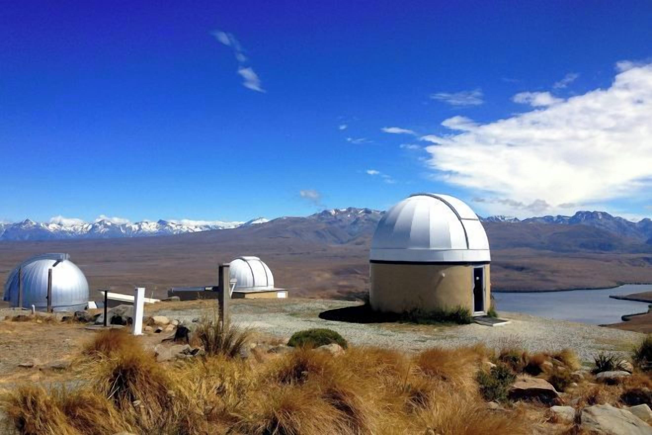 A remote observatory with domed structures and a clear view of mountains in the background.