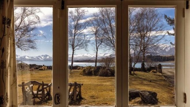 Ein Fenster mit Blick auf eine natürliche Landschaft, Bäume und Berge.