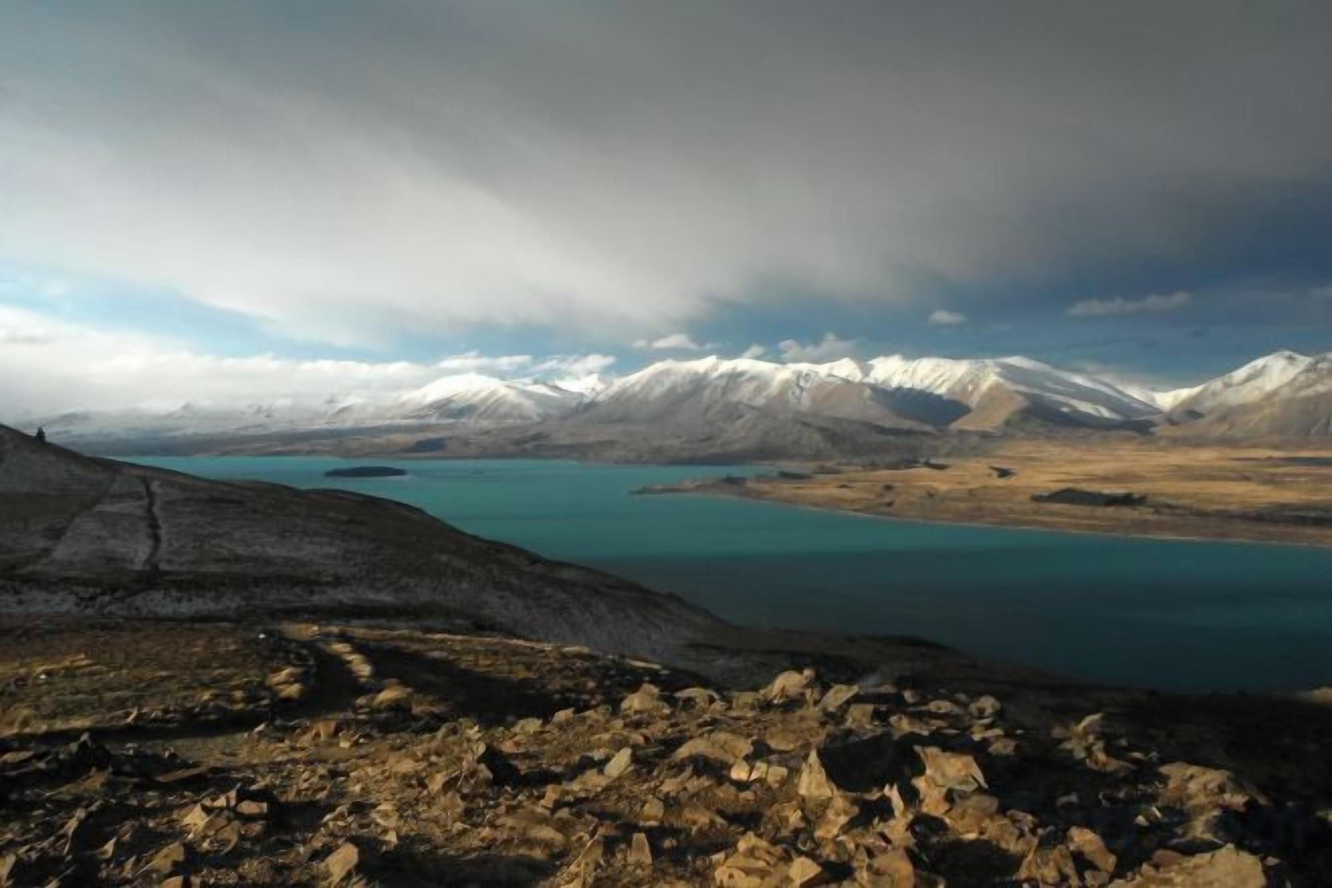 A mountainous landscape with a lake and snow-capped peaks.