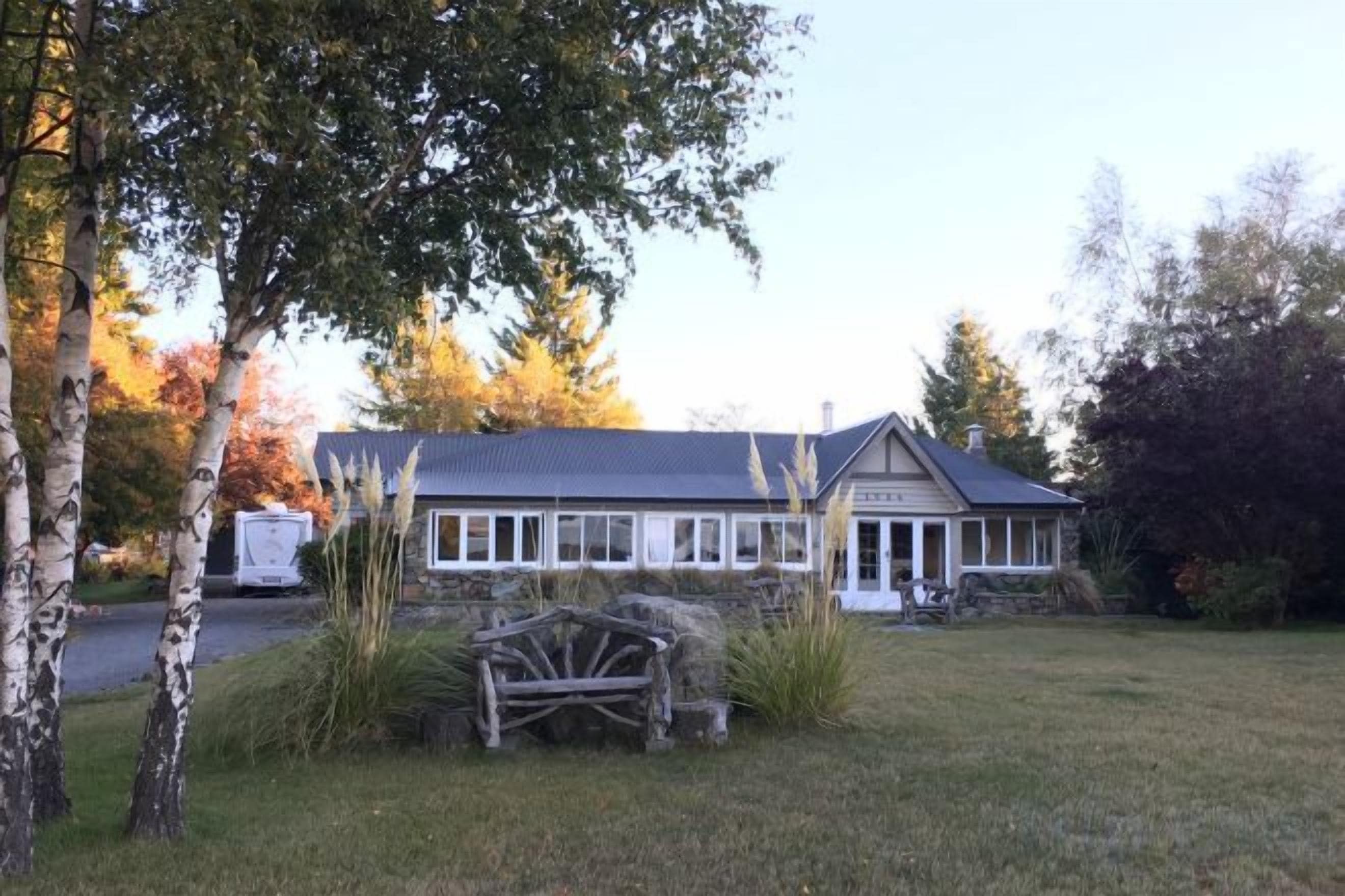 A house with a porch, surrounded by a grassy lawn and trees.