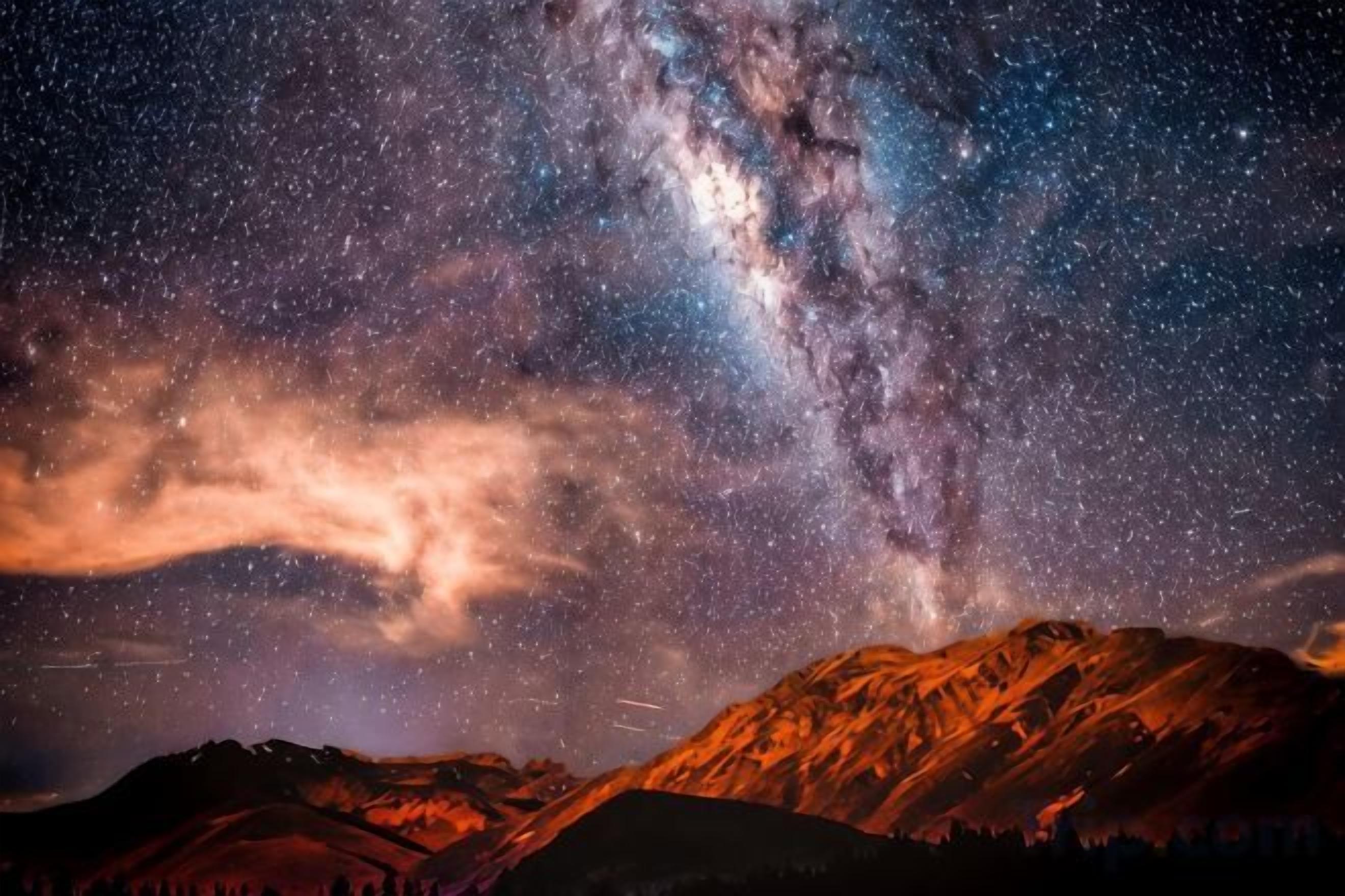 A starry night sky with a visible Milky Way over a mountainous landscape.