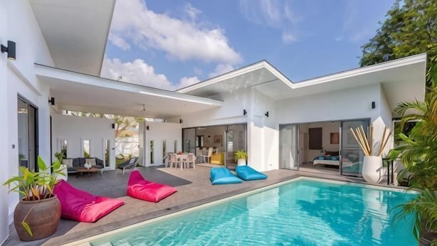 Une maison moderne dotée d’une piscine, d’un espace salon extérieur et d’un patio.