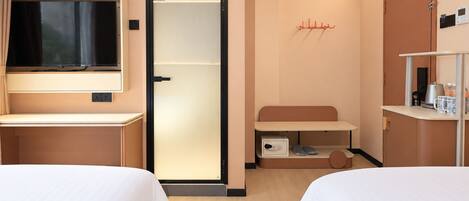 Une chambre d’hôtel avec deux lits, une télévision, une armoire, un bureau et un meuble pour ranger les chaussures.