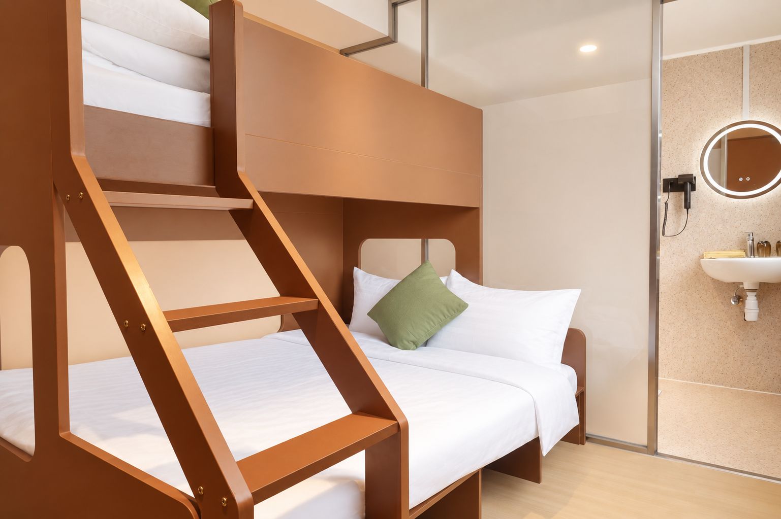 Ein Stockbett mit einer Leiter, ein Einzelbett mit Kissen, ein runder Spiegel und ein Waschbecken in einem modernen Badezimmer.