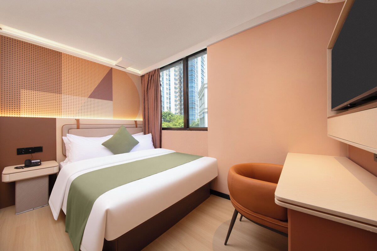Una habitación de hotel moderna con cama, mesita de noche, silla y escritorio.